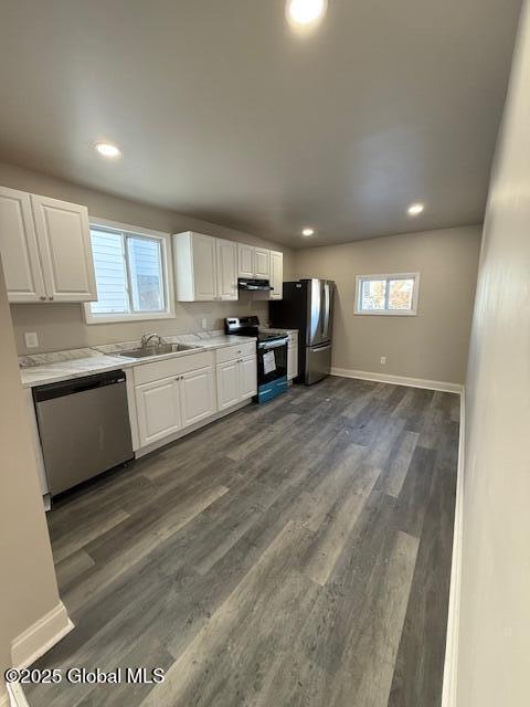 kitchen with sink, dark wood-type flooring, range hood, stainless steel appliances, and white cabinets