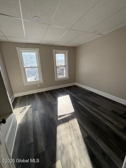 empty room with dark wood-type flooring and a paneled ceiling