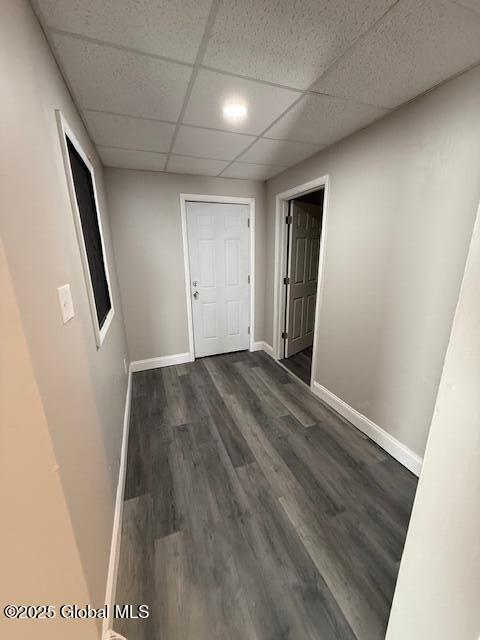 corridor with dark wood-type flooring and a paneled ceiling