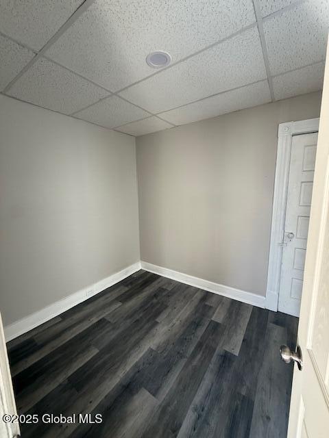 spare room featuring a paneled ceiling and dark hardwood / wood-style floors