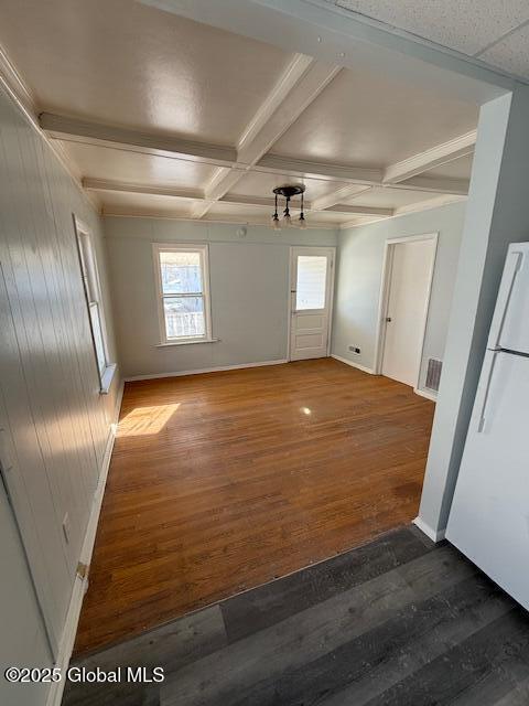 spare room with dark hardwood / wood-style floors, a healthy amount of sunlight, coffered ceiling, and beamed ceiling