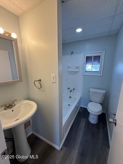 bathroom with shower / tub combination, a paneled ceiling, hardwood / wood-style floors, and toilet