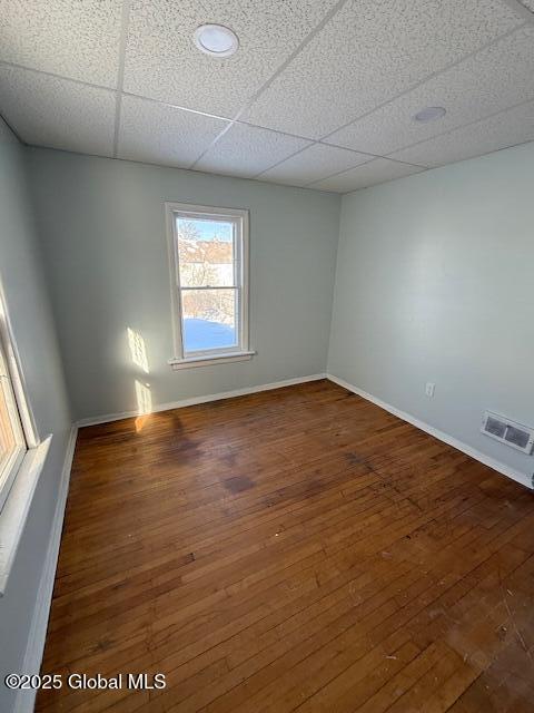 spare room featuring a paneled ceiling and dark hardwood / wood-style flooring