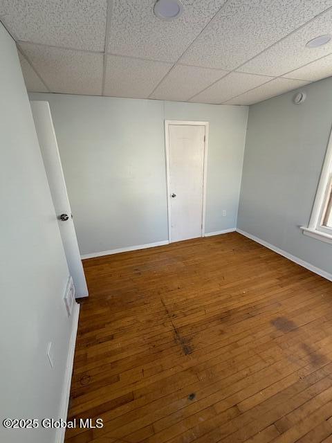 unfurnished room with a paneled ceiling and wood-type flooring