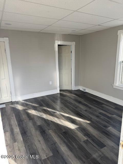 empty room with a paneled ceiling and dark hardwood / wood-style floors