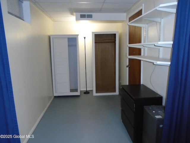 interior space with baseboards, finished concrete flooring, visible vents, and a paneled ceiling