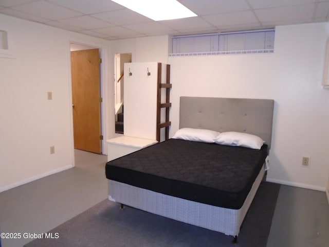 bedroom with a drop ceiling and baseboards