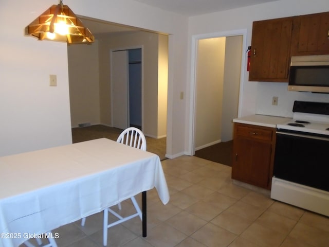 kitchen featuring stainless steel microwave, brown cabinets, range with electric cooktop, and light countertops