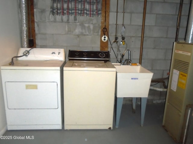 clothes washing area featuring laundry area, concrete block wall, water heater, and washer and clothes dryer