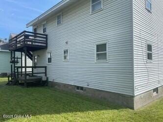 view of side of property with a yard, a wooden deck, and stairs