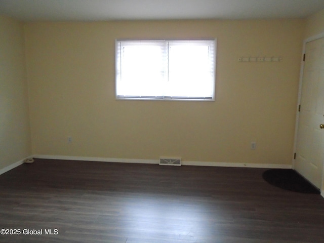 spare room with visible vents, baseboards, and wood finished floors