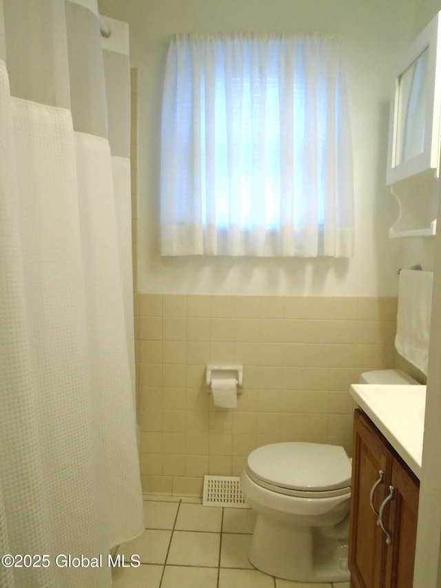 full bathroom featuring tile patterned flooring, visible vents, toilet, and tile walls