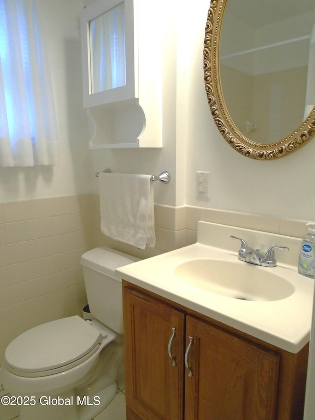 bathroom featuring toilet, tile walls, and vanity