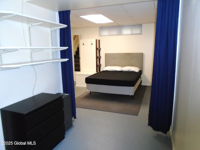 bedroom with finished concrete flooring and a paneled ceiling