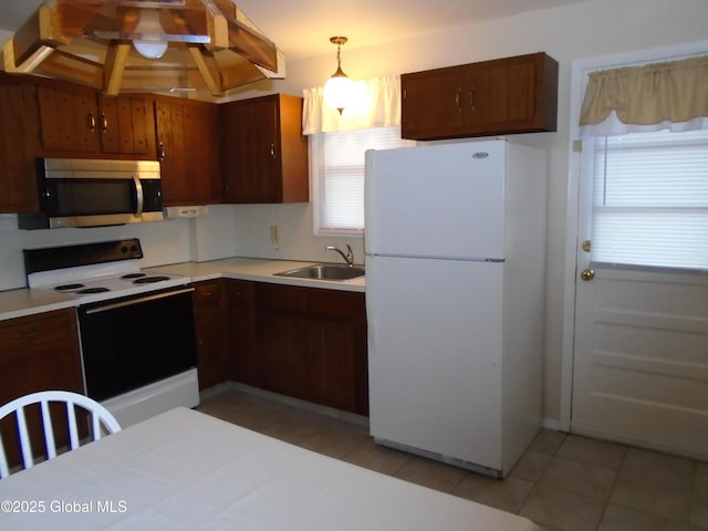 kitchen with electric range, a sink, stainless steel microwave, freestanding refrigerator, and light countertops