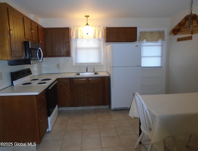 kitchen featuring electric stove, a sink, stainless steel microwave, plenty of natural light, and freestanding refrigerator