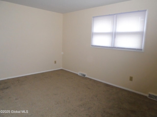 carpeted spare room featuring visible vents and baseboards