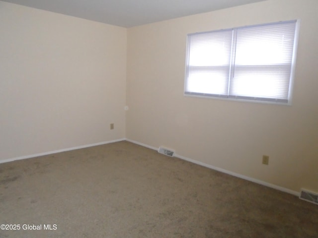 empty room featuring carpet, baseboards, and visible vents