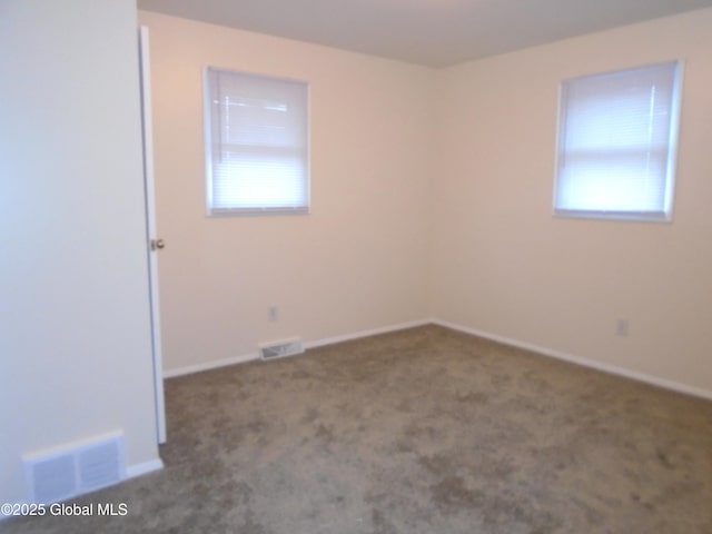 carpeted spare room featuring a healthy amount of sunlight, visible vents, and baseboards