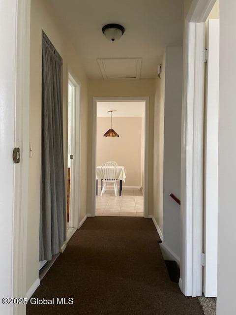 hallway with baseboards, carpet, attic access, and tile patterned flooring