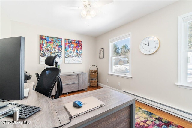 home office featuring ceiling fan, wood-type flooring, and a baseboard heating unit