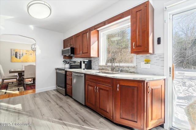 kitchen featuring tasteful backsplash, appliances with stainless steel finishes, sink, and light hardwood / wood-style floors