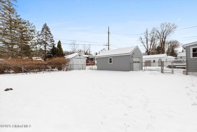 yard layered in snow with a garage and an outbuilding