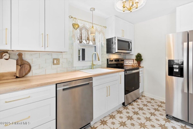 kitchen featuring butcher block counters, sink, appliances with stainless steel finishes, pendant lighting, and white cabinets