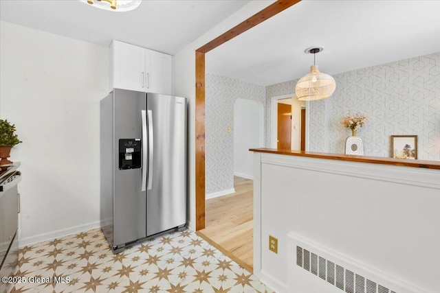 kitchen with radiator, white cabinets, hanging light fixtures, baseboard heating, and stainless steel refrigerator with ice dispenser