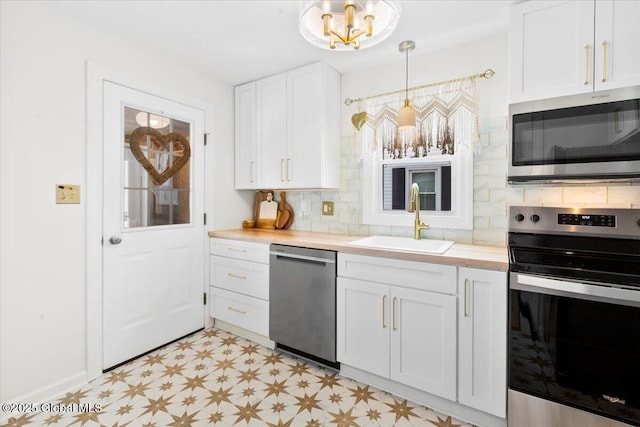 kitchen featuring white cabinetry, sink, decorative light fixtures, and appliances with stainless steel finishes