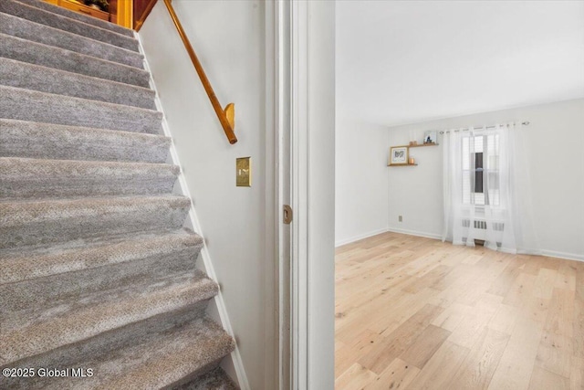 staircase featuring hardwood / wood-style flooring and radiator heating unit