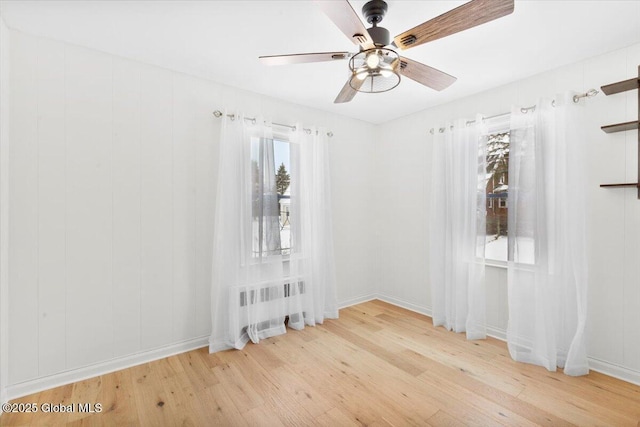 spare room featuring ceiling fan, radiator, and light hardwood / wood-style floors