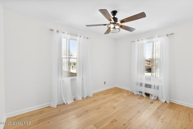 unfurnished room with ceiling fan, radiator, and light wood-type flooring