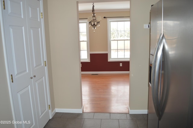 kitchen featuring pendant lighting, crown molding, stainless steel refrigerator with ice dispenser, tile patterned floors, and an inviting chandelier