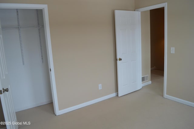 unfurnished bedroom with light carpet and a closet