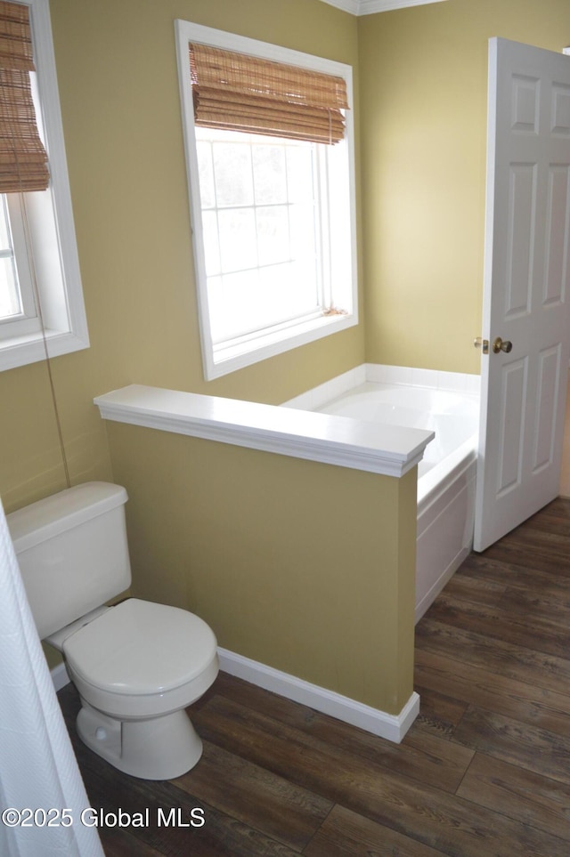 bathroom with toilet, hardwood / wood-style floors, and a tub