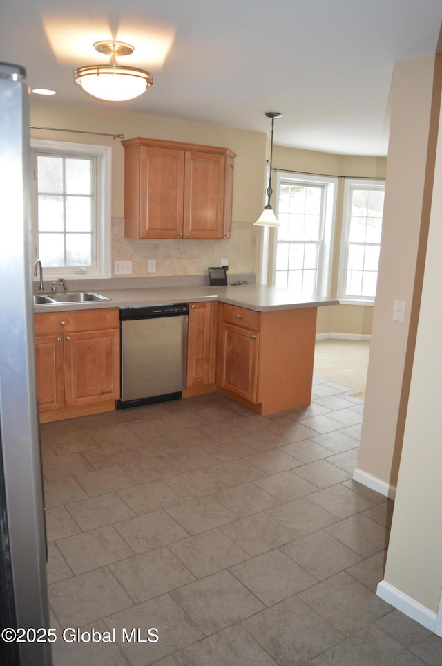 kitchen with appliances with stainless steel finishes, decorative light fixtures, sink, decorative backsplash, and kitchen peninsula