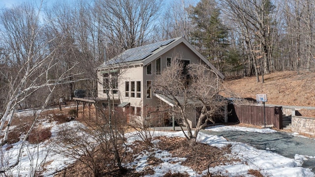 snow covered property with roof mounted solar panels and metal roof