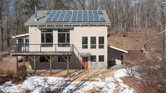 view of front facade featuring a shingled roof and roof mounted solar panels