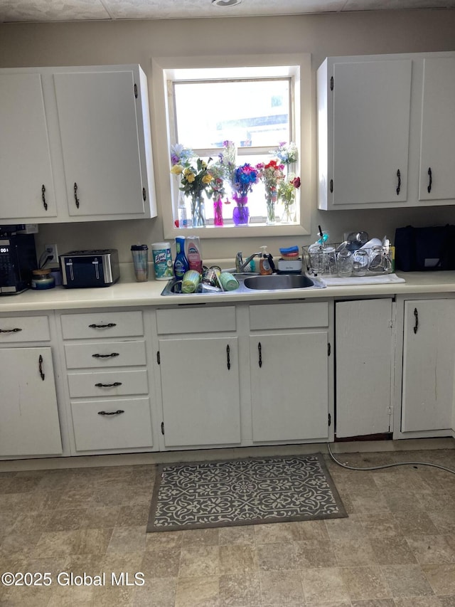 kitchen with light countertops, a sink, and white cabinetry