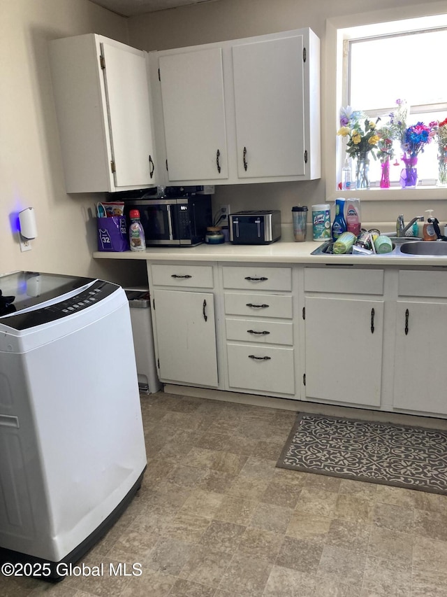 kitchen with white cabinets, light countertops, and a sink