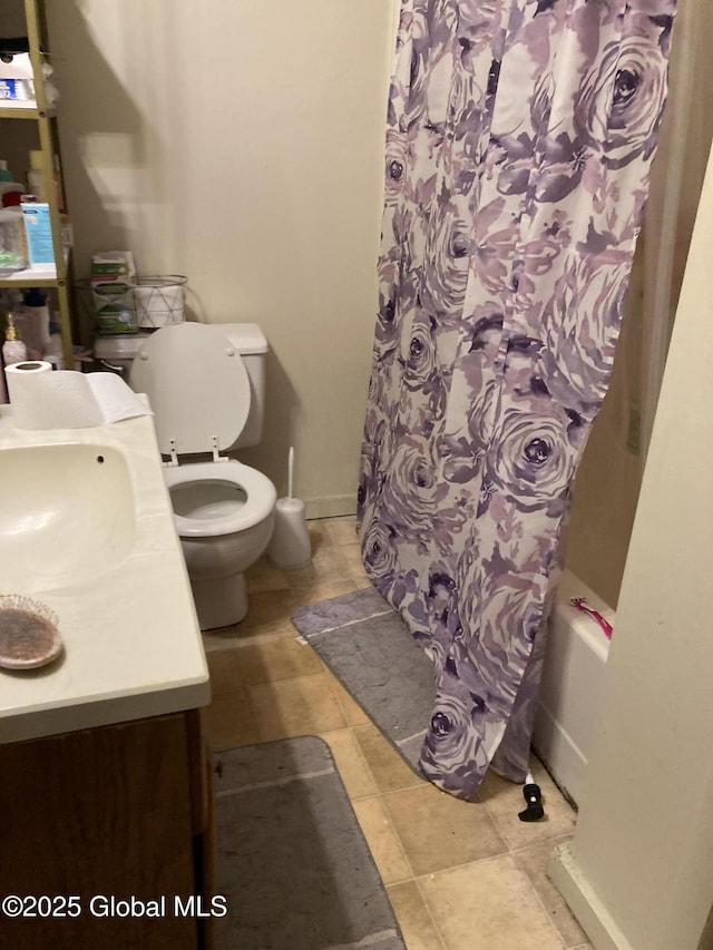 bathroom featuring shower / bath combination with curtain, vanity, toilet, and baseboards