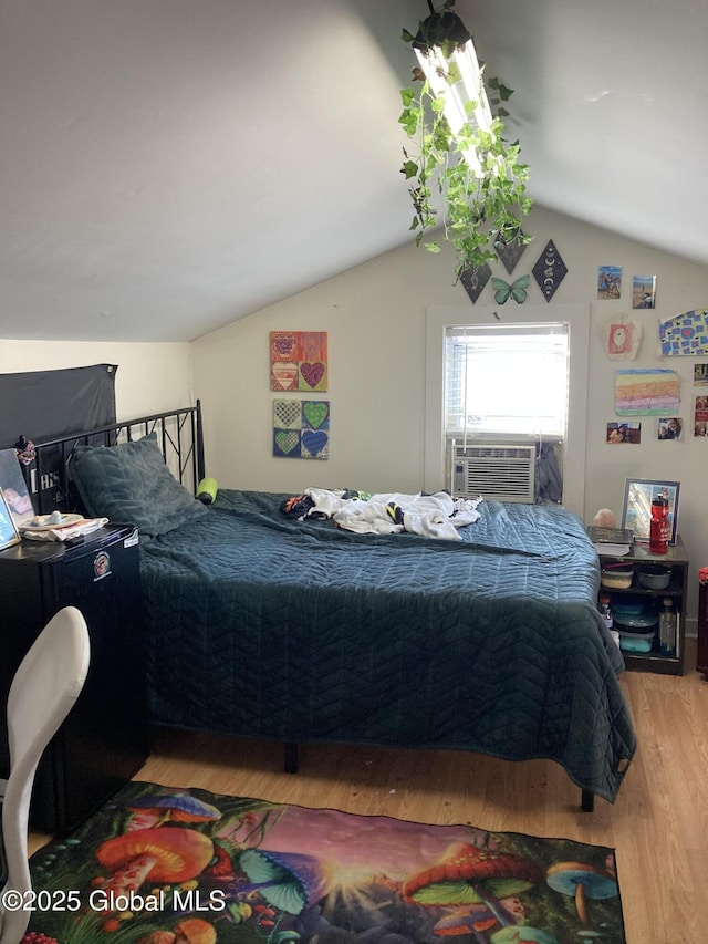 bedroom with light wood-style floors, cooling unit, and vaulted ceiling