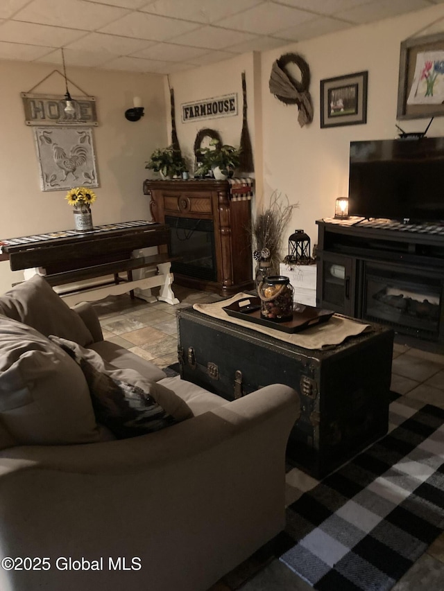 living room with a paneled ceiling and a fireplace