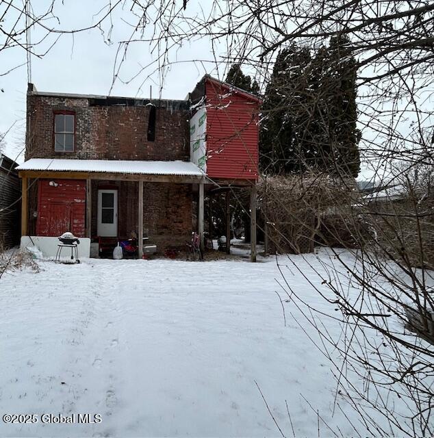 snow covered house featuring covered porch