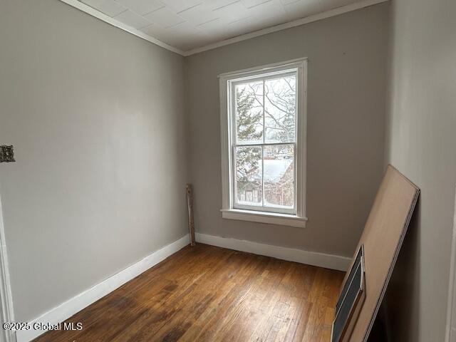 unfurnished room featuring dark hardwood / wood-style flooring, plenty of natural light, and ornamental molding