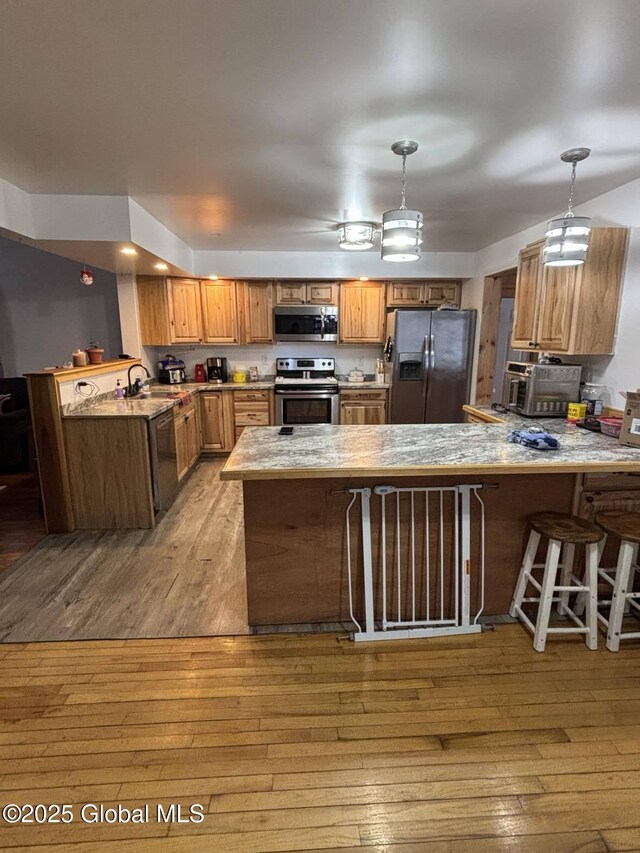 86 Reid St, Fort Plain, NY 13339 - kitchen with light wood-type flooring, appliances with stainless steel finishes, a peninsula, and hanging light fixtures