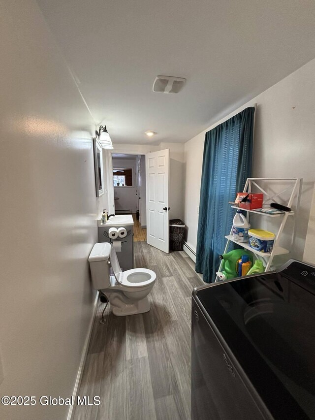 86 Reid St, Fort Plain, NY 13339 - bathroom with baseboards, toilet, baseboard heating, washer / dryer, and wood finished floors