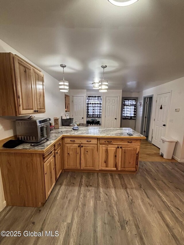 86 Reid St, Fort Plain, NY 13339 - kitchen featuring a chandelier, a peninsula, wood finished floors, and hanging light fixtures