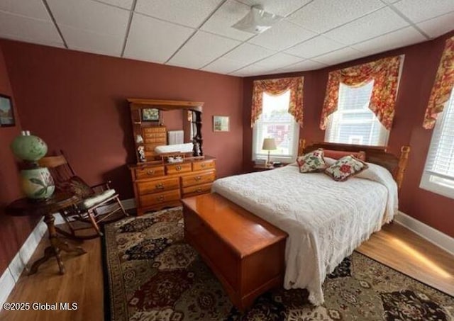 bedroom with a drop ceiling and wood-type flooring